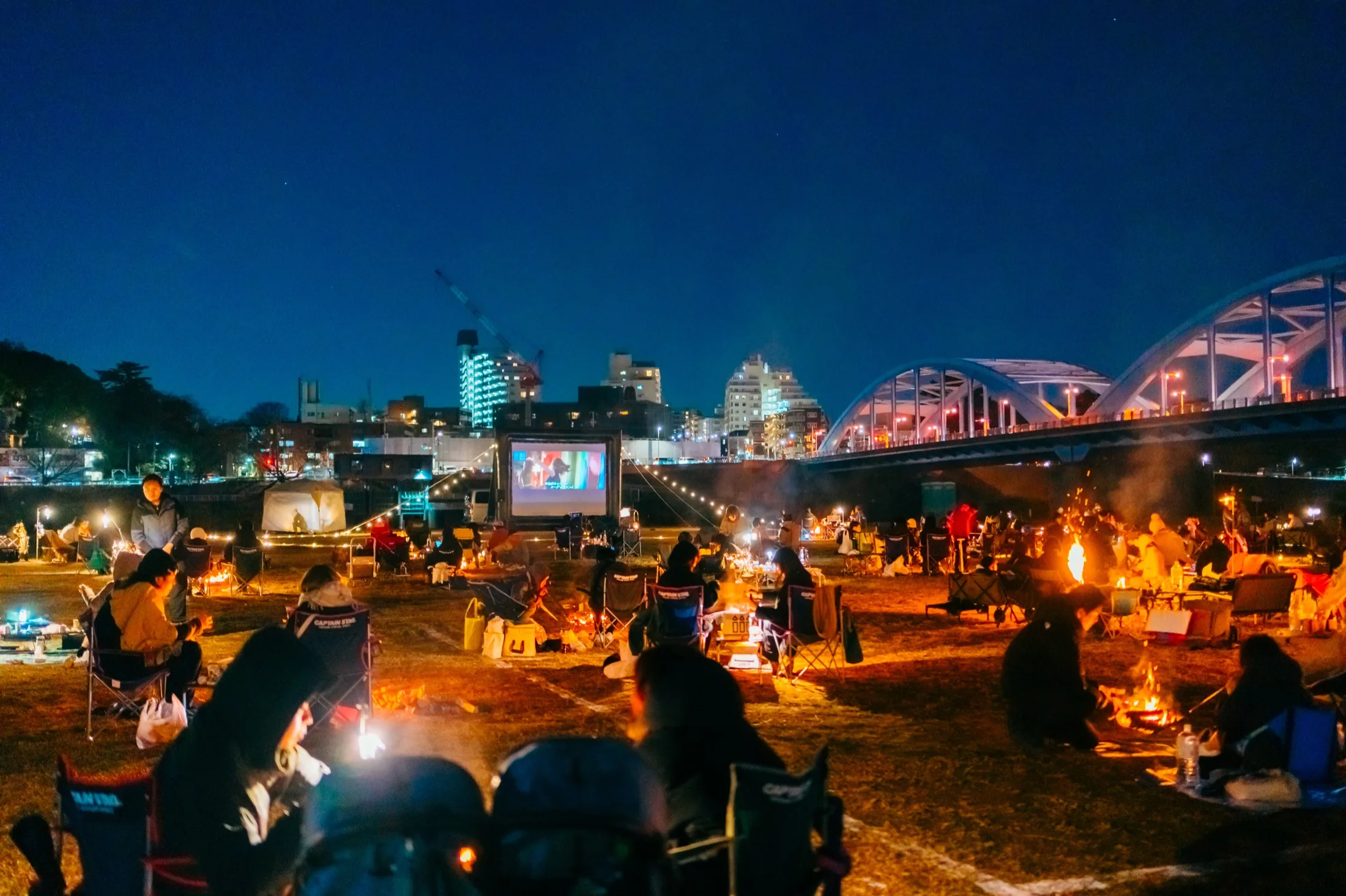 丸子橋の夜景を背景に焚き火を楽しむ会場